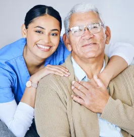 A caregiver with her arm around a smiling older man