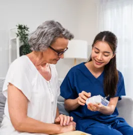 A nurse explaining a medication to an older woman at home