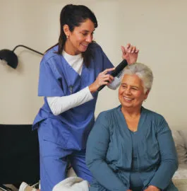 A caregiver combing an older woman’s hair